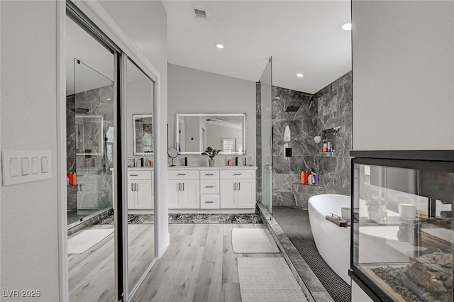 bathroom featuring visible vents, a tile shower, vanity, wood finished floors, and a freestanding tub