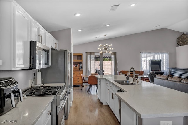 kitchen with lofted ceiling, appliances with stainless steel finishes, a sink, and visible vents