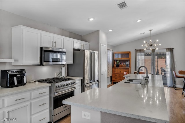 kitchen featuring visible vents, appliances with stainless steel finishes, a kitchen island with sink, white cabinets, and a sink