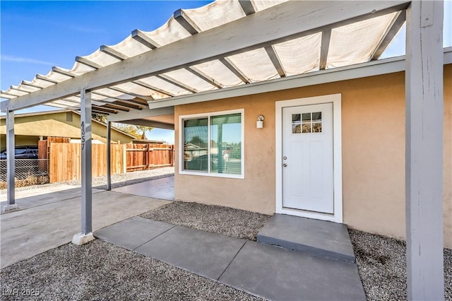 doorway to property with fence and stucco siding