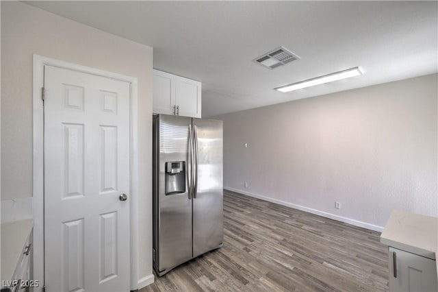 kitchen with wood finished floors, white cabinetry, visible vents, light countertops, and stainless steel fridge with ice dispenser