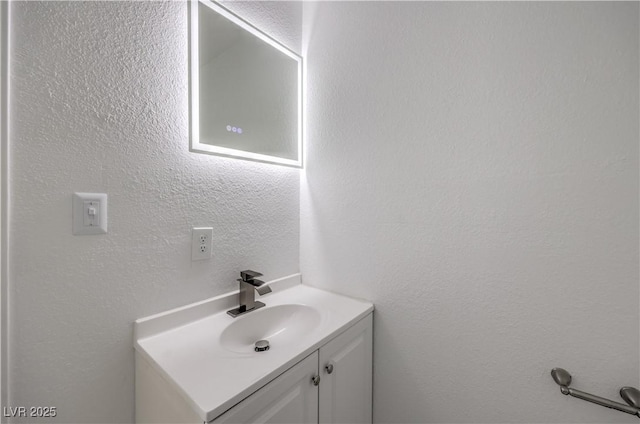 bathroom with a textured wall and vanity