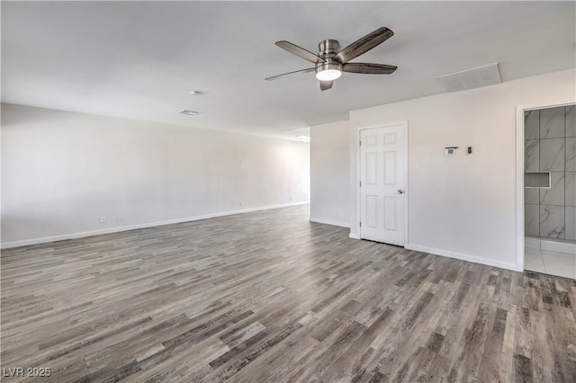 spare room featuring ceiling fan, visible vents, baseboards, and wood finished floors