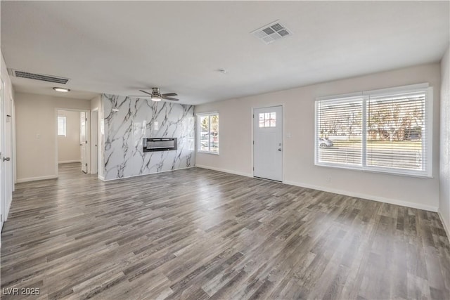 unfurnished living room with baseboards, wood finished floors, visible vents, and a ceiling fan