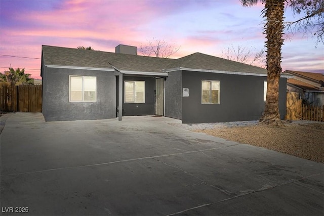 single story home featuring stucco siding, roof with shingles, concrete driveway, and fence