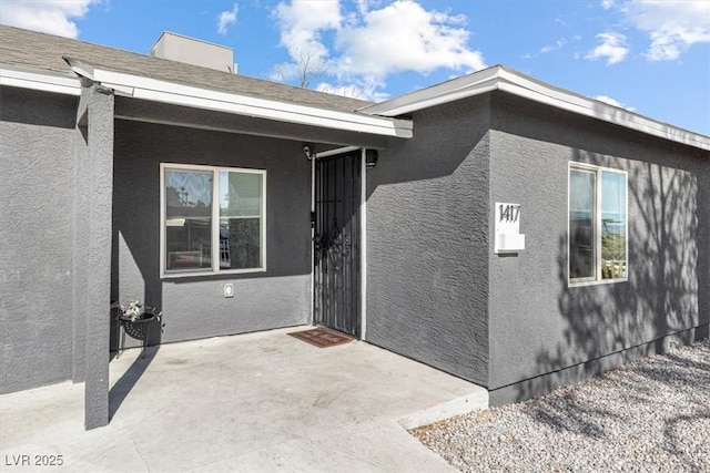 entrance to property featuring a patio area and stucco siding