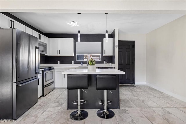 kitchen featuring a kitchen island, a breakfast bar, light countertops, white cabinets, and appliances with stainless steel finishes