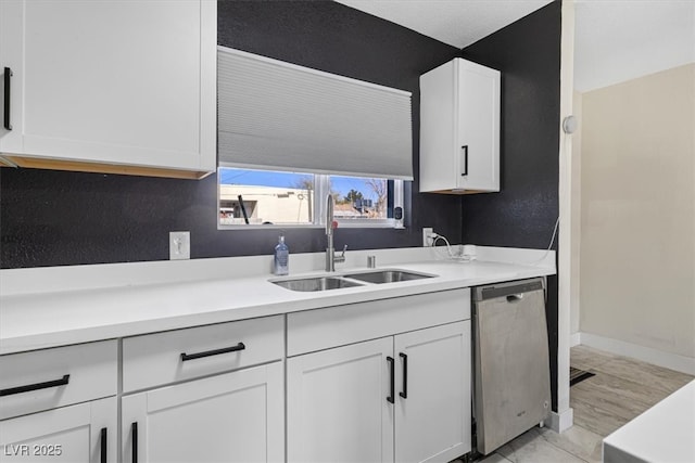 kitchen featuring baseboards, a sink, light countertops, white cabinets, and dishwasher