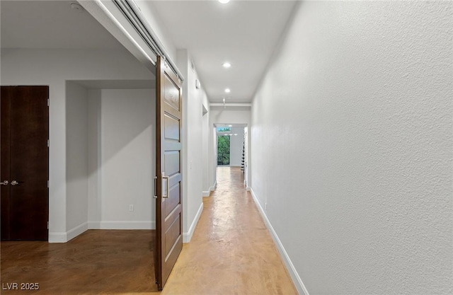 hall with recessed lighting, a textured wall, and baseboards