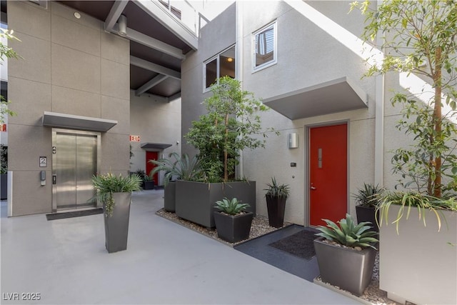 view of exterior entry featuring elevator and stucco siding