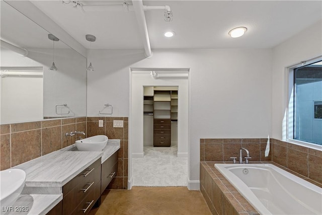 full bath with double vanity, a garden tub, tile walls, and a sink