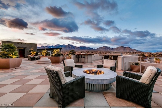 view of patio featuring an outdoor fire pit and a mountain view