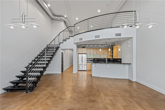 kitchen with visible vents, a towering ceiling, dark countertops, stainless steel appliances, and concrete flooring