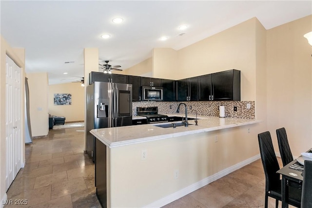 kitchen featuring a sink, light countertops, appliances with stainless steel finishes, dark cabinetry, and backsplash