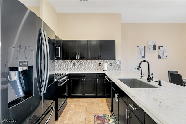 kitchen with a sink, stainless steel fridge with ice dispenser, dark cabinetry, decorative backsplash, and black gas range oven