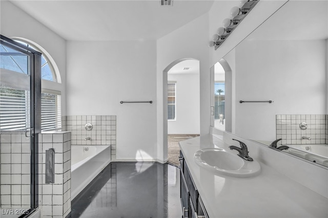 full bathroom with baseboards, visible vents, a garden tub, finished concrete floors, and vanity