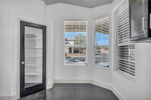 empty room with baseboards and finished concrete floors