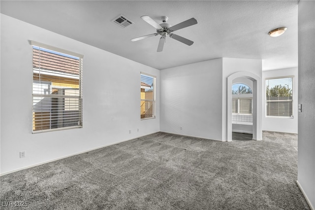 carpeted empty room with ceiling fan, a textured ceiling, and visible vents