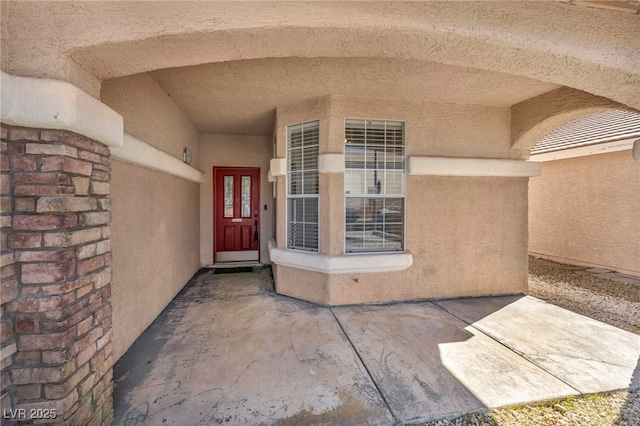 view of exterior entry featuring a patio and stucco siding