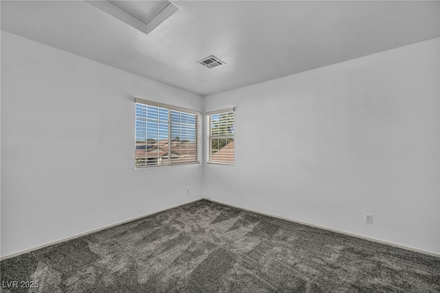 unfurnished room with carpet flooring, visible vents, and a textured ceiling