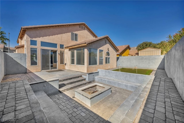 back of property with a patio area, a fenced backyard, a fire pit, and stucco siding