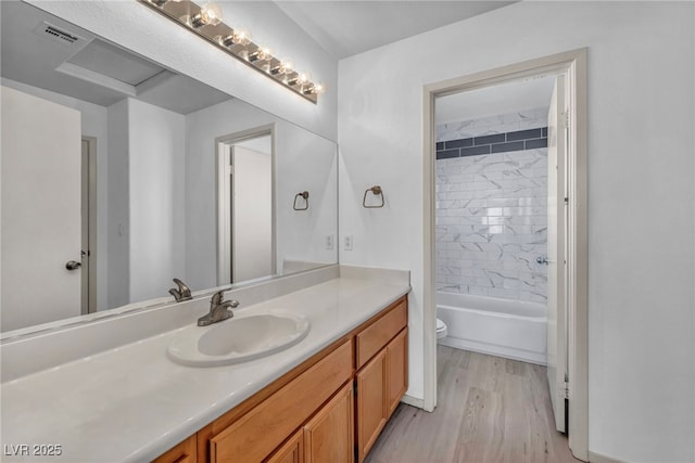 bathroom featuring bathtub / shower combination, visible vents, toilet, vanity, and wood finished floors