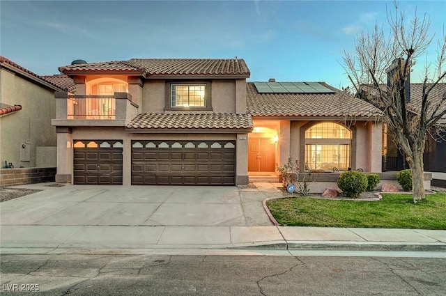 mediterranean / spanish-style home with stucco siding, concrete driveway, roof mounted solar panels, a balcony, and a garage