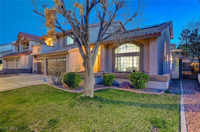 mediterranean / spanish-style home with a garage, concrete driveway, roof mounted solar panels, a front lawn, and stucco siding