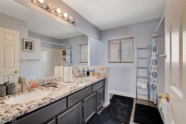 full bath featuring a shower with curtain, a sink, baseboards, and double vanity