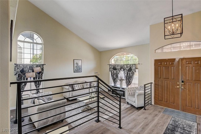 foyer entrance featuring high vaulted ceiling, wood finished floors, and an inviting chandelier