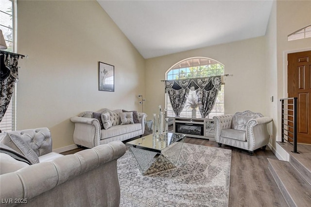 living room with high vaulted ceiling, baseboards, and wood finished floors