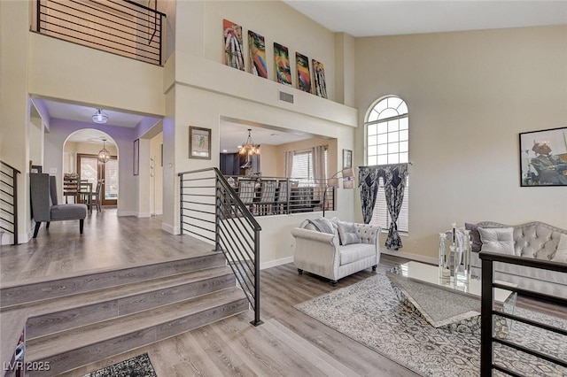 interior space with arched walkways, baseboards, wood finished floors, and a notable chandelier