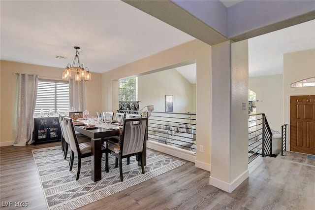 dining area featuring baseboards, visible vents, a chandelier, and wood finished floors