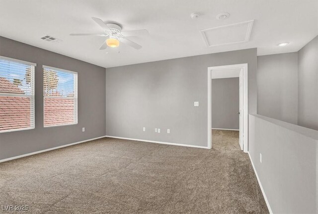 spare room with attic access, carpet flooring, visible vents, and baseboards