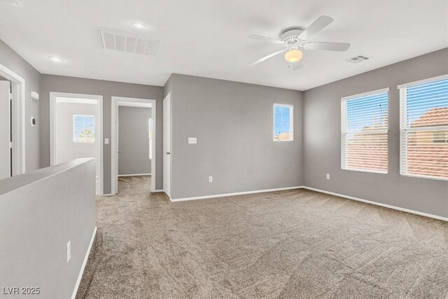 spare room featuring carpet floors, visible vents, baseboards, and a ceiling fan