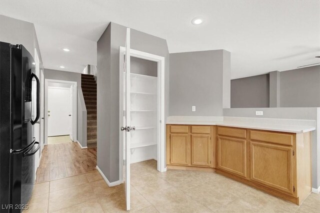 kitchen with light tile patterned floors, light countertops, black fridge, and recessed lighting