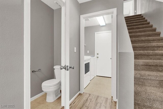 bathroom featuring wood finished floors, visible vents, toilet, and separate washer and dryer