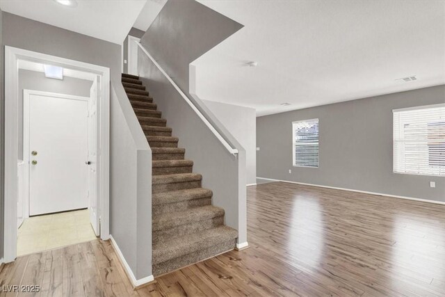 stairway with baseboards, visible vents, and wood finished floors