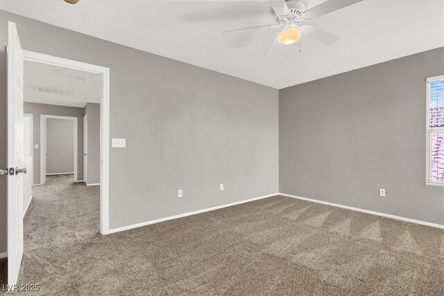 carpeted empty room with ceiling fan, visible vents, and baseboards