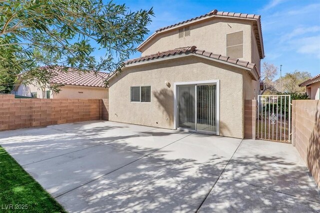 rear view of property featuring fence, a patio, and stucco siding