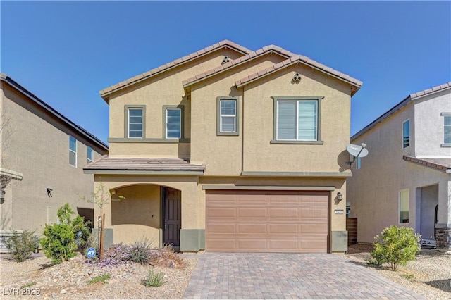 view of front of property with a garage, decorative driveway, a tile roof, and stucco siding