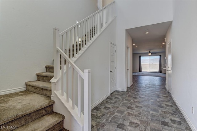 stairway featuring a ceiling fan, recessed lighting, a towering ceiling, and baseboards