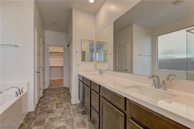 bathroom with visible vents, double vanity, a sink, and a bath