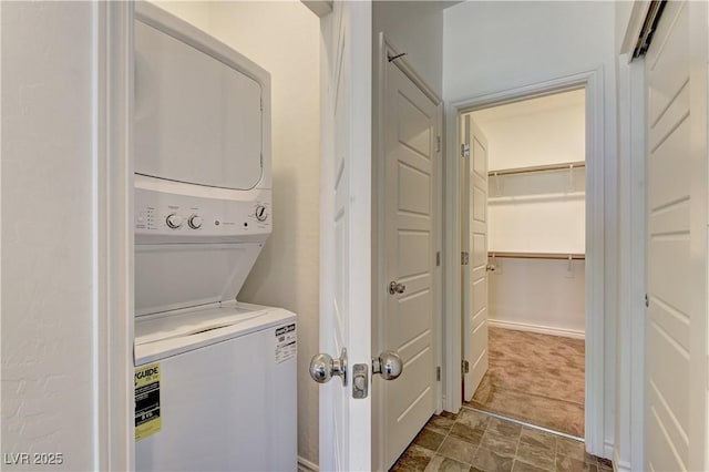 laundry area with laundry area, dark carpet, and stacked washer and clothes dryer