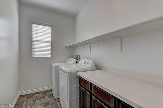 clothes washing area featuring washer and dryer, laundry area, stone finish floor, and baseboards