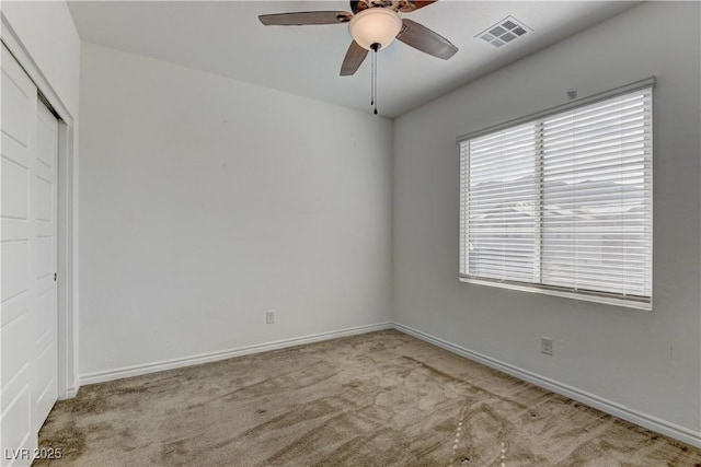 spare room featuring a ceiling fan, carpet, visible vents, and baseboards