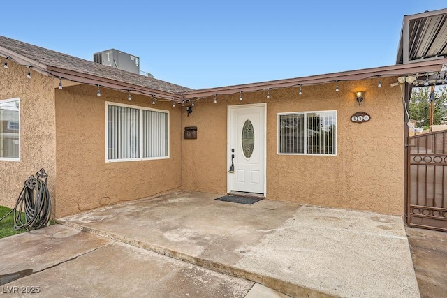 property entrance featuring a patio area, fence, and stucco siding