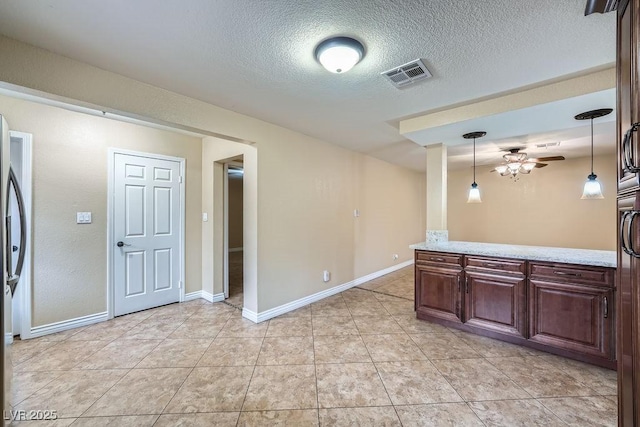 kitchen with a textured ceiling, decorative light fixtures, visible vents, and baseboards