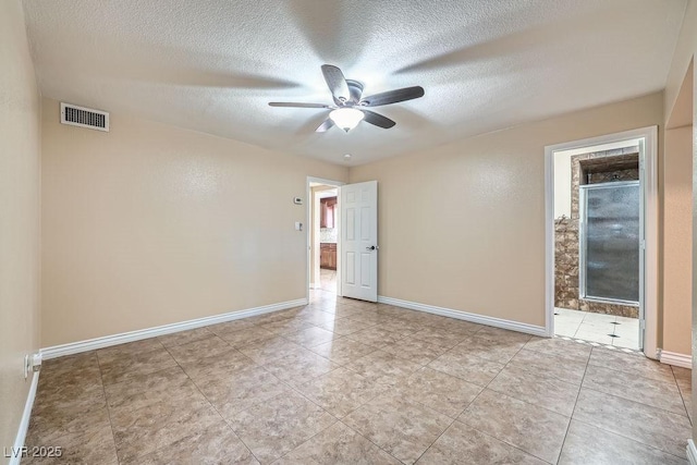 tiled spare room with a ceiling fan, visible vents, a textured ceiling, and baseboards