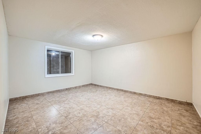 empty room featuring light tile patterned floors, baseboards, and a textured ceiling